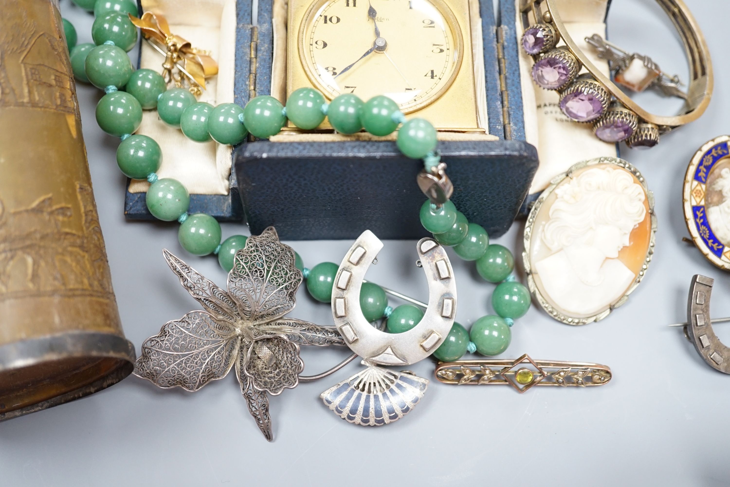 A small collection of jewellery including a silver horseshoe brooch, 9ct suspension brooch, gross 2.8 grams, and a travelling bedside timepiece and beaker.